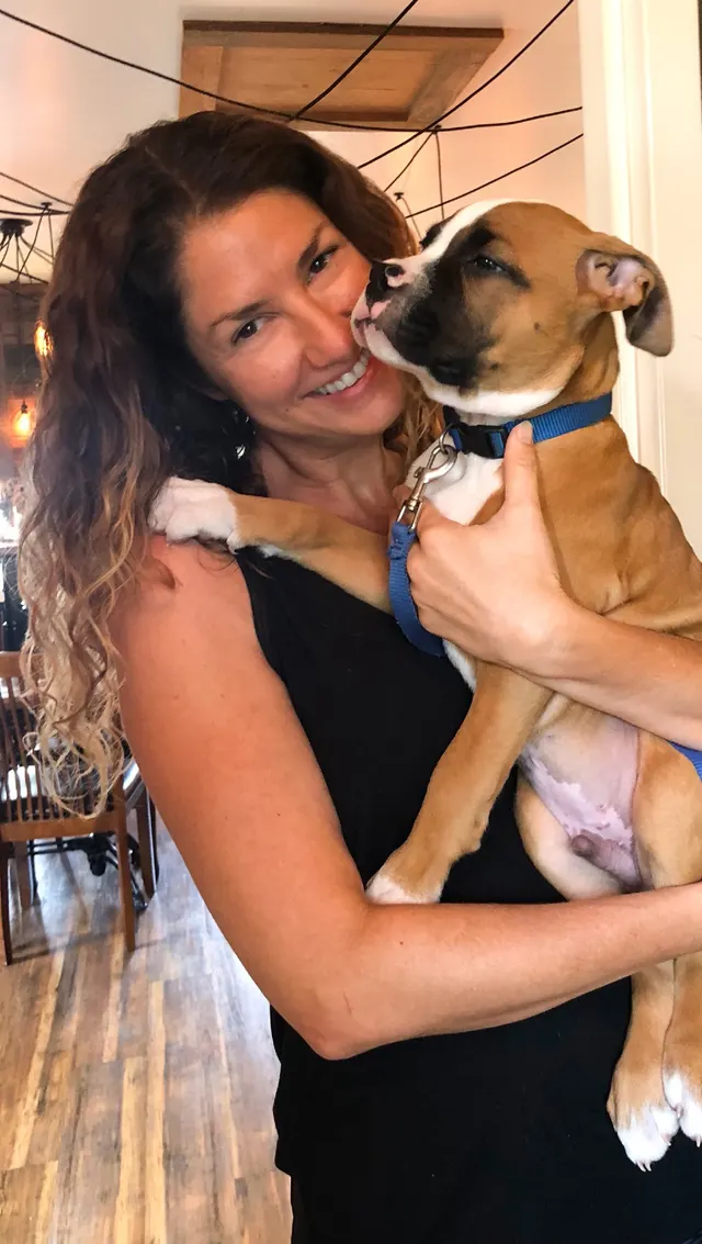 A FurKid walker hugging a boxer puppy